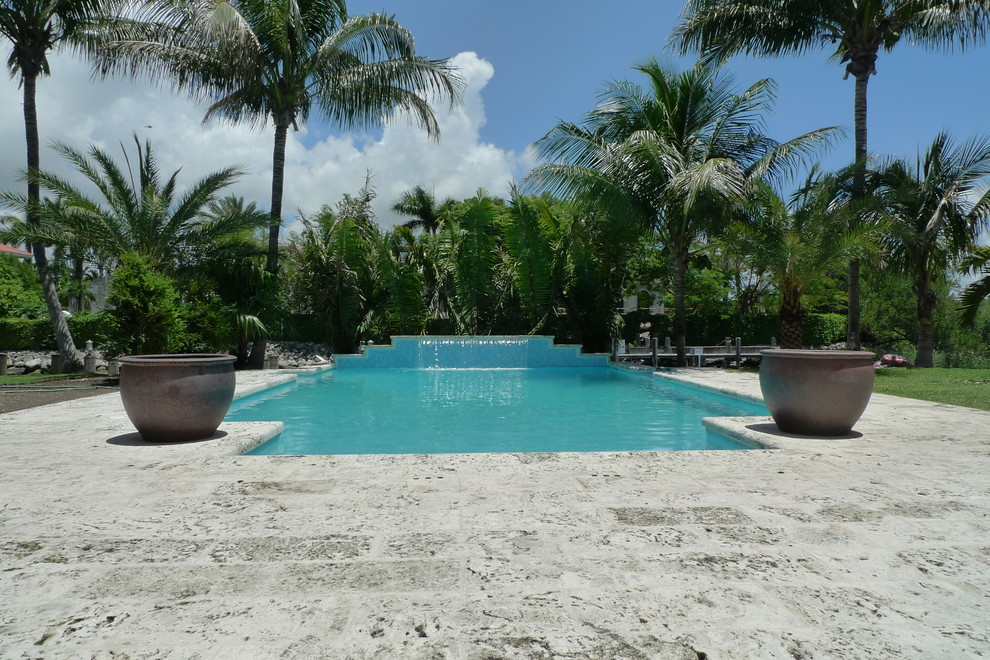 Photo of a large asian side yard pool in Miami with natural stone pavers.
