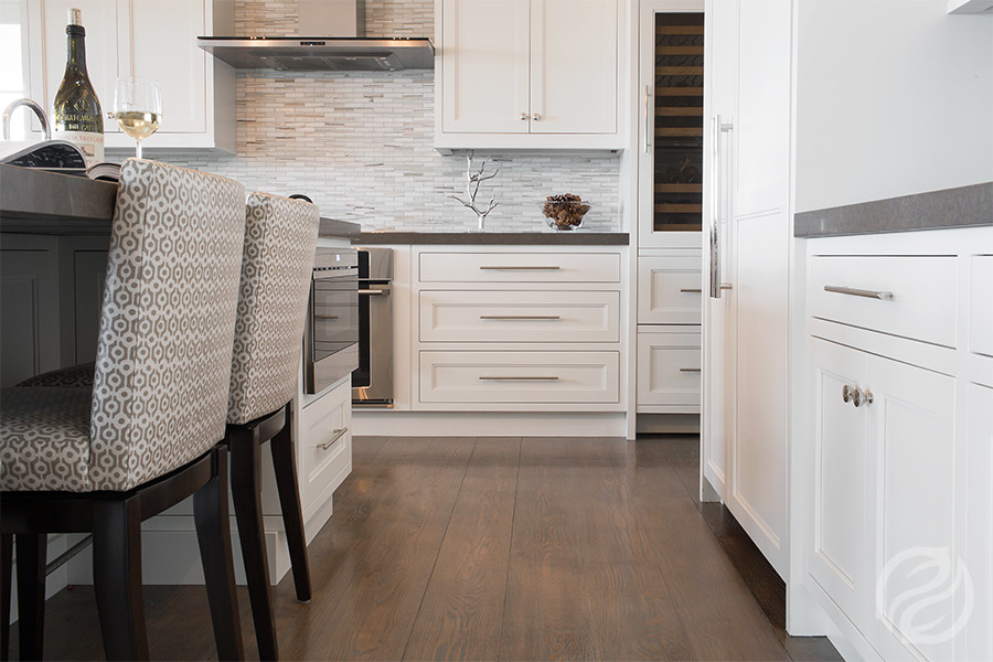 Transitional u-shaped medium tone wood floor kitchen photo in Boston with white cabinets, paneled appliances and an island