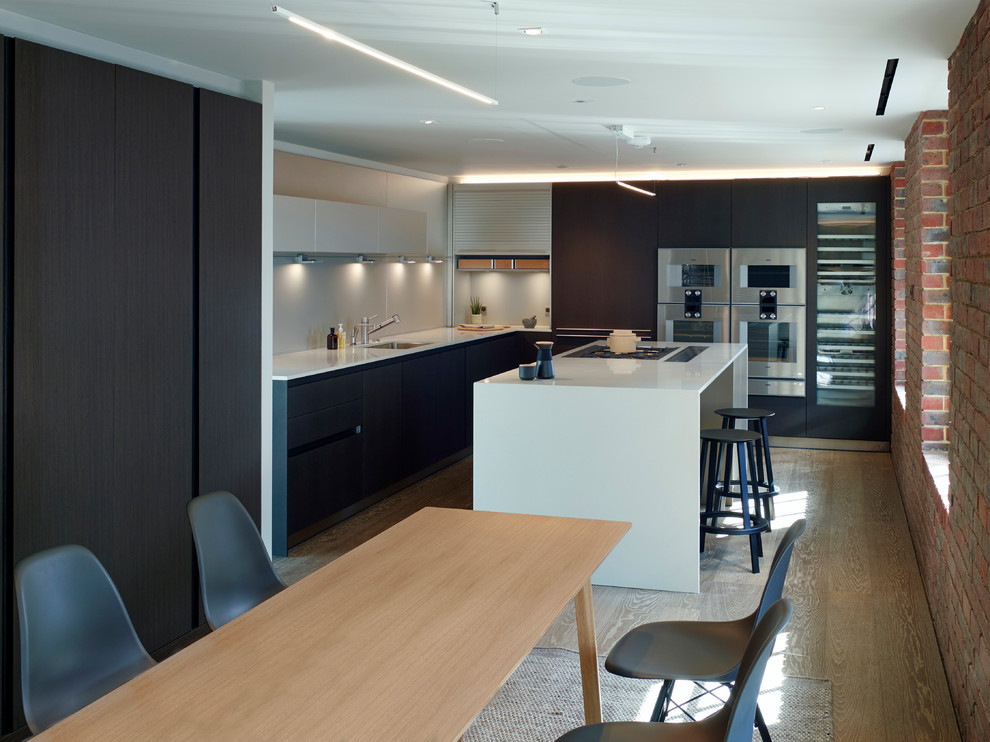 Photo of a mid-sized contemporary kitchen/dining combo in London with grey walls and light hardwood floors.