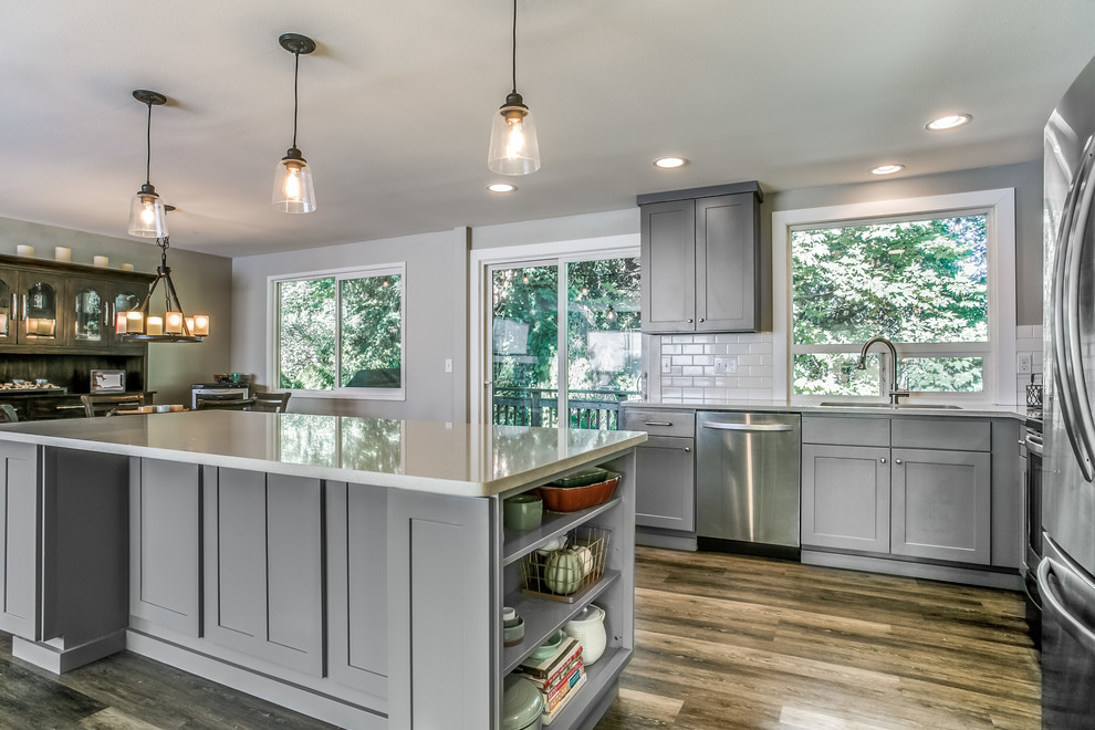 Eat-in kitchen - mid-sized transitional l-shaped laminate floor and brown floor eat-in kitchen idea in Seattle with an undermount sink, shaker cabinets, gray cabinets, quartz countertops, white backsplash, subway tile backsplash, stainless steel appliances and an island