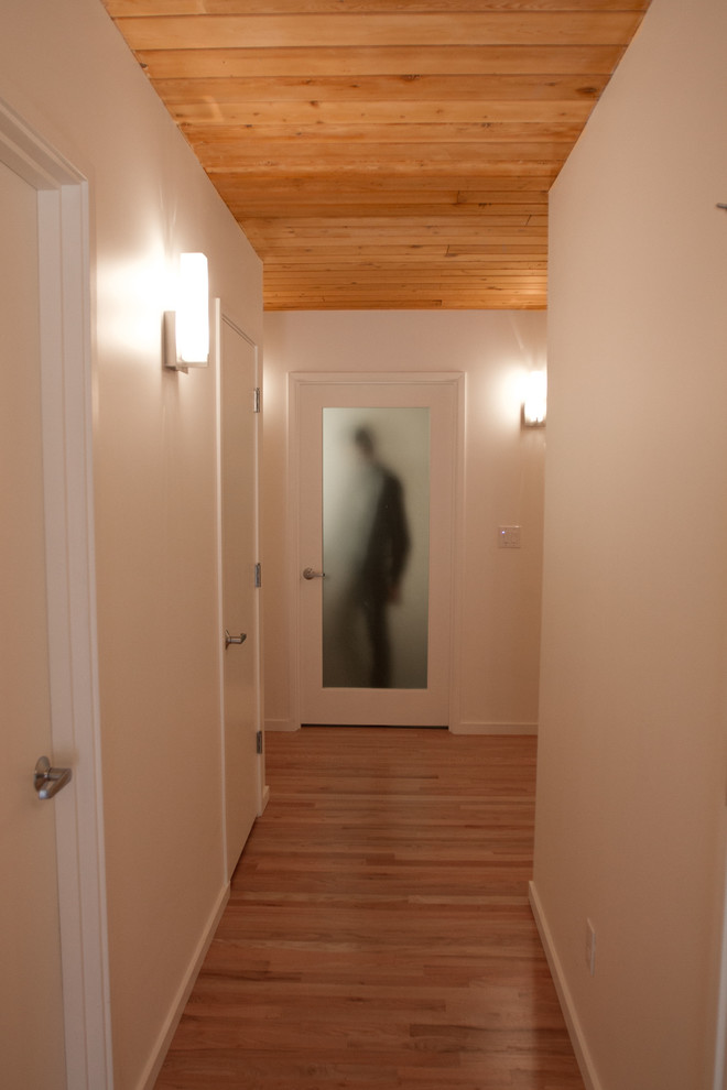 This is an example of a midcentury hallway in Portland with white walls and light hardwood floors.