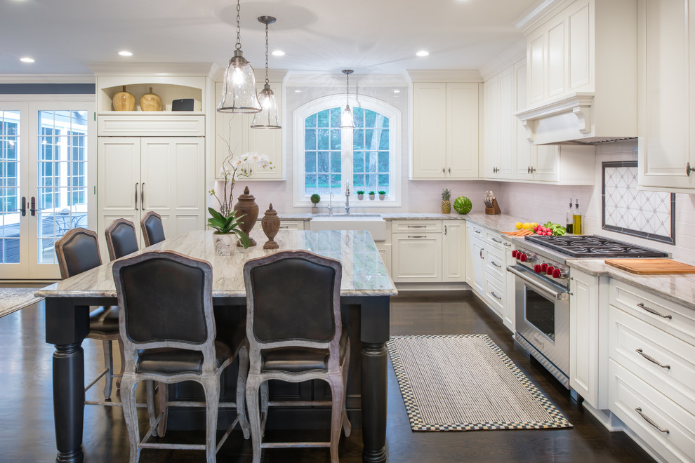 Mid-sized country l-shaped eat-in kitchen in Minneapolis with a farmhouse sink, raised-panel cabinets, white cabinets, grey splashback, stainless steel appliances, dark hardwood floors, with island, brown floor, granite benchtops and ceramic splashback.