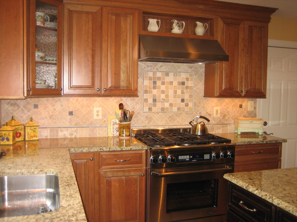 Photo of a mid-sized traditional l-shaped eat-in kitchen in DC Metro with raised-panel cabinets, medium wood cabinets, multi-coloured splashback, stainless steel appliances, medium hardwood floors and with island.