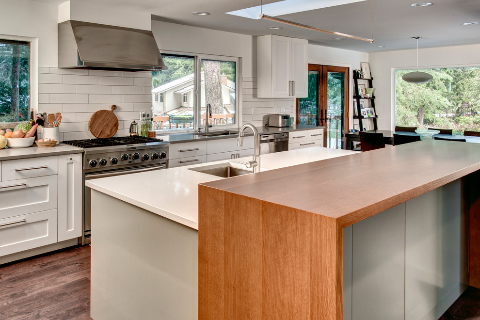 Transitional l-shaped medium tone wood floor open concept kitchen photo in Seattle with an undermount sink, shaker cabinets, white cabinets, quartz countertops, white backsplash, subway tile backsplash, stainless steel appliances and an island