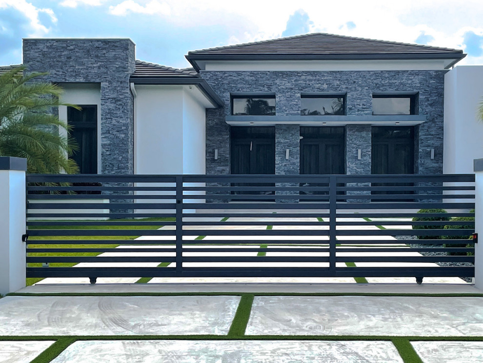 Photo of a contemporary house exterior in Miami with stone veneer.