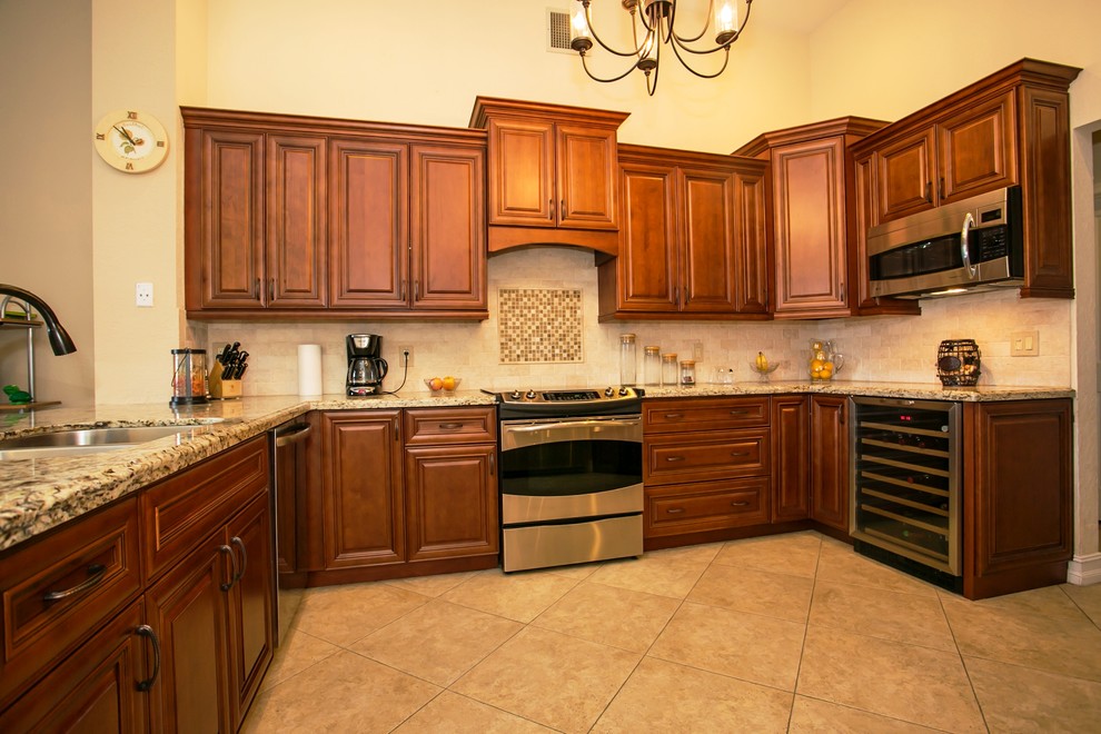 Mid-sized transitional u-shaped porcelain tile eat-in kitchen photo in Miami with an undermount sink, raised-panel cabinets, brown cabinets, granite countertops, beige backsplash, stone tile backsplash, stainless steel appliances, beige walls and a peninsula