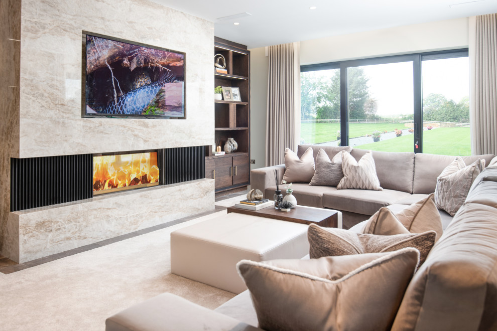 Photo of a large modern grey and cream enclosed living room curtain with beige walls, carpet, a stone fireplace surround, a built-in media unit, beige floors and curtains.