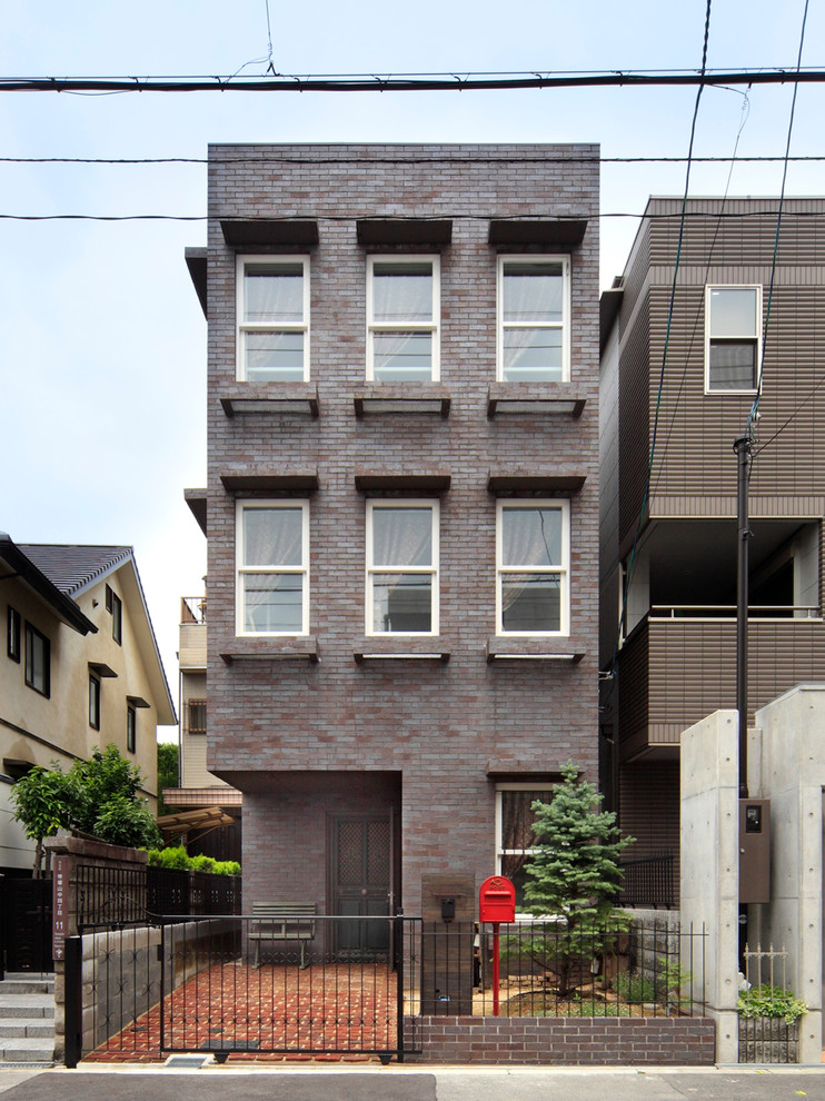 Inspiration for a transitional three-storey brick brown apartment exterior in Osaka with a flat roof.