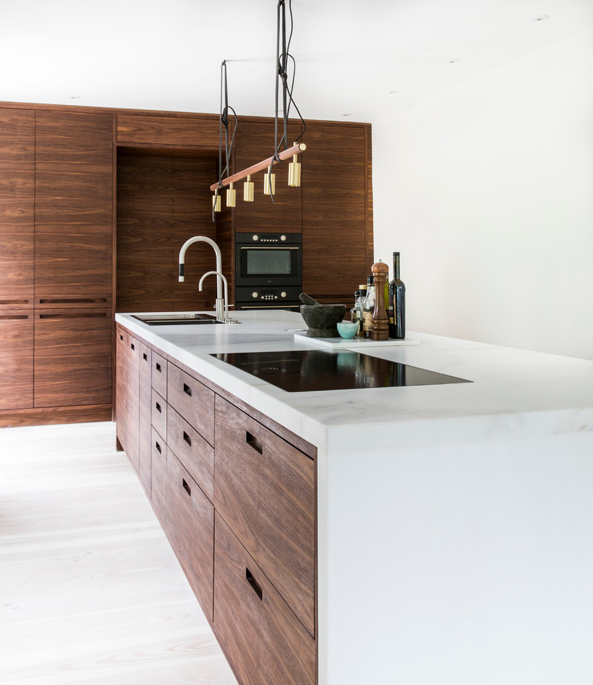 Photo of a large contemporary single-wall separate kitchen in Copenhagen with a double-bowl sink, flat-panel cabinets, dark wood cabinets, marble benchtops, black appliances, light hardwood floors and with island.