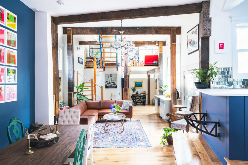 This is an example of an industrial living room in Boston with blue walls, light hardwood flooring and exposed beams.
