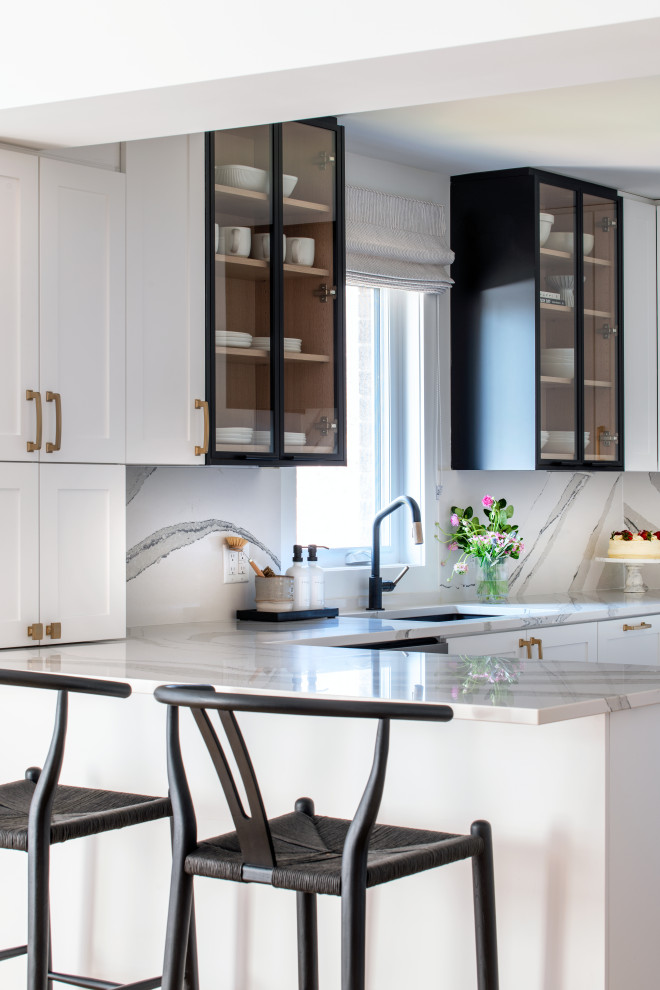 Example of a mid-sized transitional u-shaped medium tone wood floor eat-in kitchen design with an undermount sink, shaker cabinets, white cabinets, quartz countertops, white backsplash, quartz backsplash, stainless steel appliances, a peninsula and white countertops