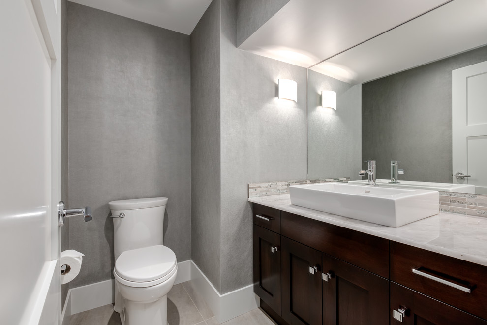 This is an example of a contemporary bathroom in Calgary with shaker cabinets, dark wood cabinets, matchstick tile, grey walls, porcelain floors, a vessel sink and marble benchtops.