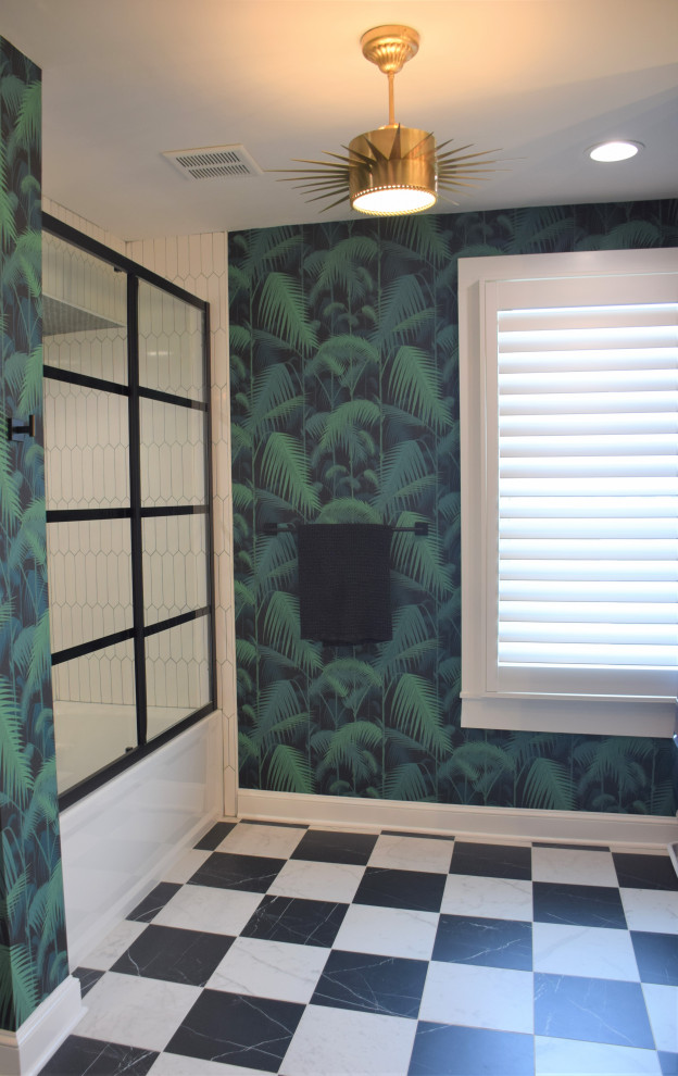 Photo of a small tropical master bathroom in Baltimore with flat-panel cabinets, medium wood cabinets, an alcove tub, an alcove shower, a two-piece toilet, white tile, porcelain tile, green walls, porcelain floors, an undermount sink, engineered quartz benchtops, black floor, a sliding shower screen, white benchtops, a laundry, a double vanity, a built-in vanity and wallpaper.