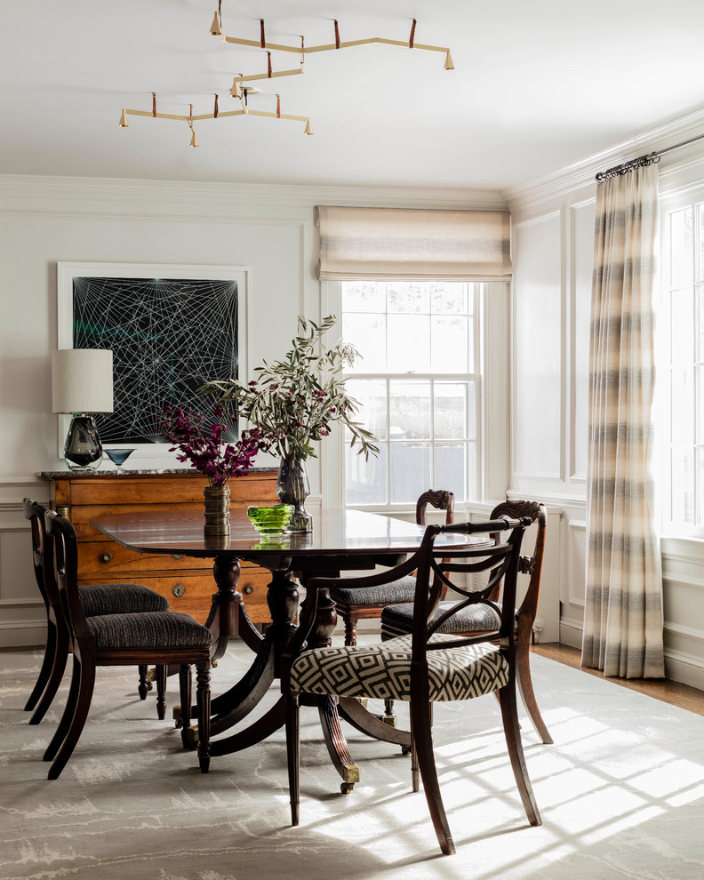 Example of a large transitional medium tone wood floor and gray floor enclosed dining room design in Boston with white walls