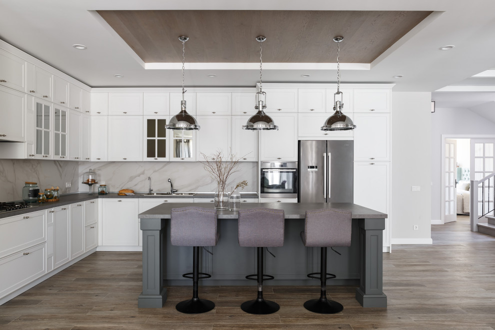 Photo of a large transitional l-shaped open plan kitchen in Moscow with a single-bowl sink, recessed-panel cabinets, white cabinets, laminate benchtops, white splashback, porcelain splashback, stainless steel appliances, porcelain floors, with island, grey floor and grey benchtop.