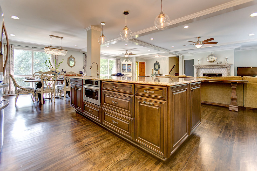 Example of a large l-shaped medium tone wood floor open concept kitchen design in Birmingham with a farmhouse sink, raised-panel cabinets, medium tone wood cabinets, granite countertops, white backsplash, ceramic backsplash, stainless steel appliances and an island