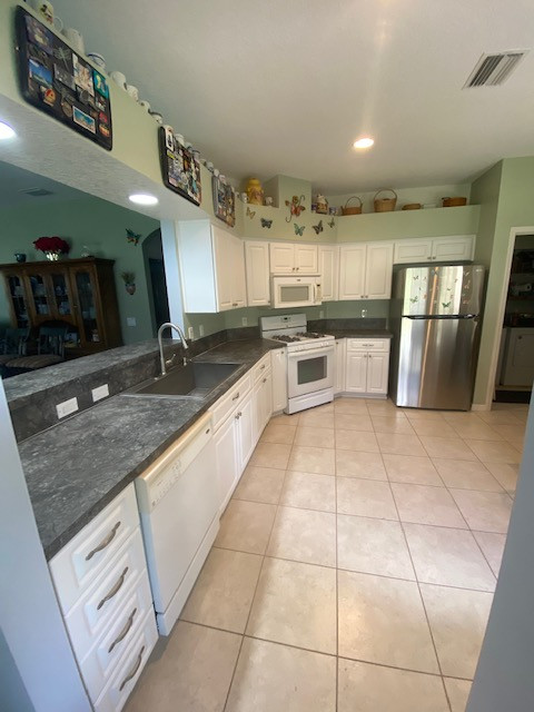 Example of a mid-sized l-shaped eat-in kitchen design with a single-bowl sink, raised-panel cabinets, white cabinets, laminate countertops, stainless steel appliances and gray countertops
