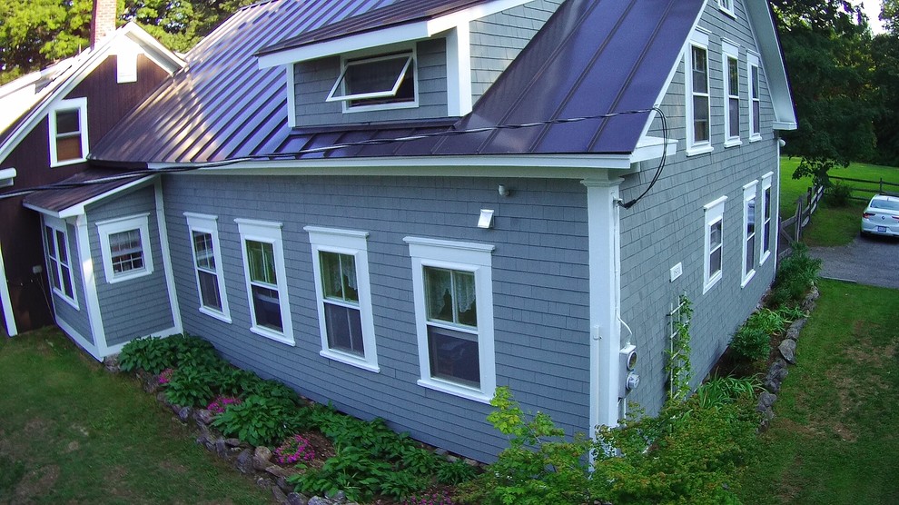 Country two-storey grey house exterior in Boston with a metal roof.