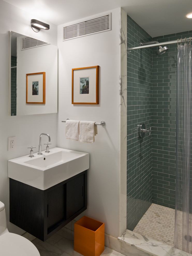 Contemporary bathroom in New York with a wall-mount sink, flat-panel cabinets, black cabinets, an alcove shower, green tile and glass tile.