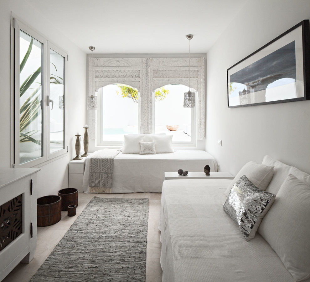 Inspiration for a mid-sized mediterranean guest bedroom in Malaga with white walls, travertine floors and no fireplace.