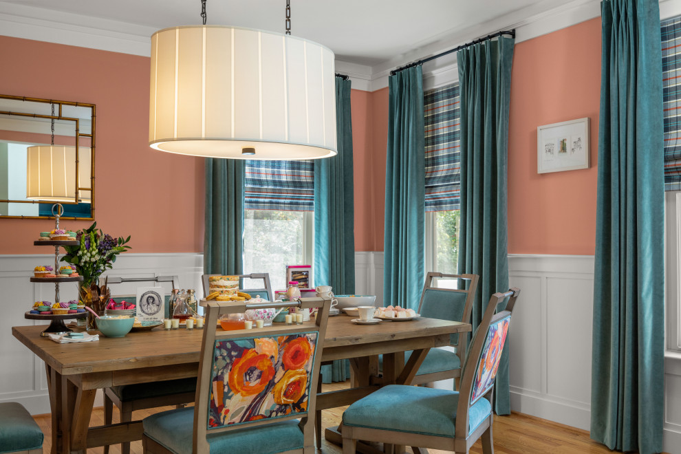 Cette photo montre une salle à manger chic avec un mur rose et un sol en bois brun.