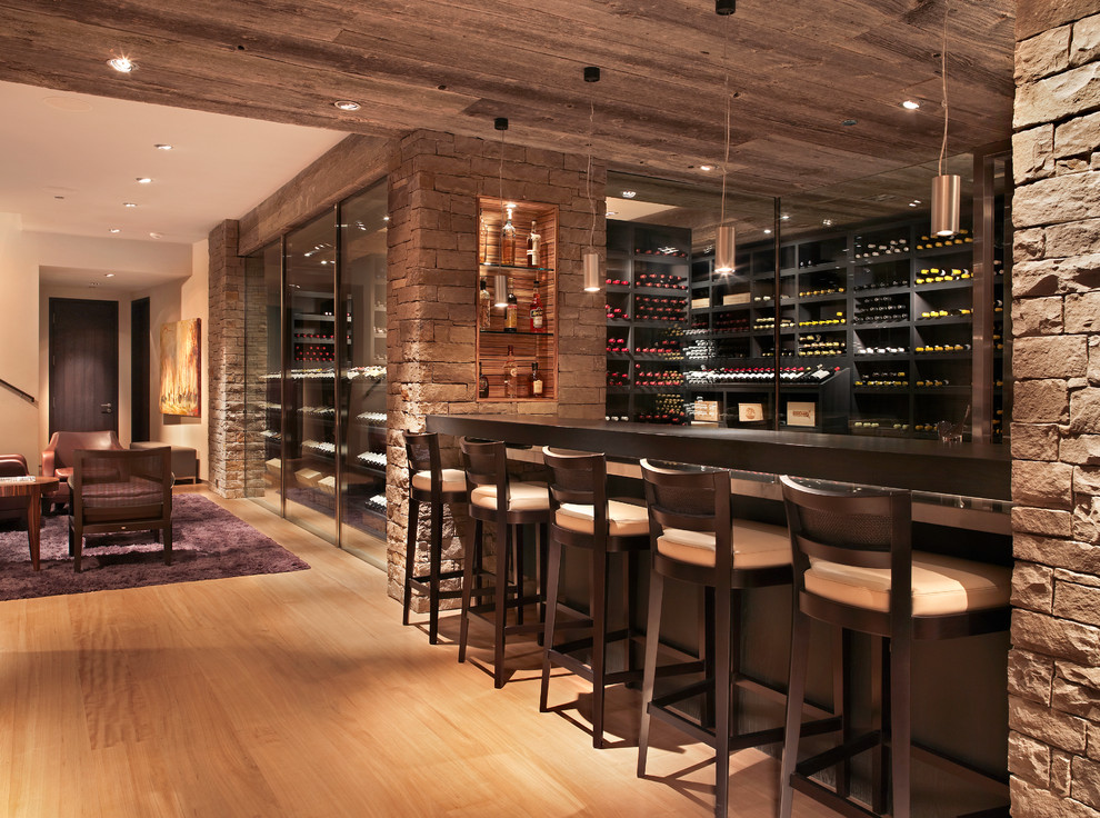 This is an example of a large contemporary wine cellar in Denver with light hardwood floors, storage racks and beige floor.