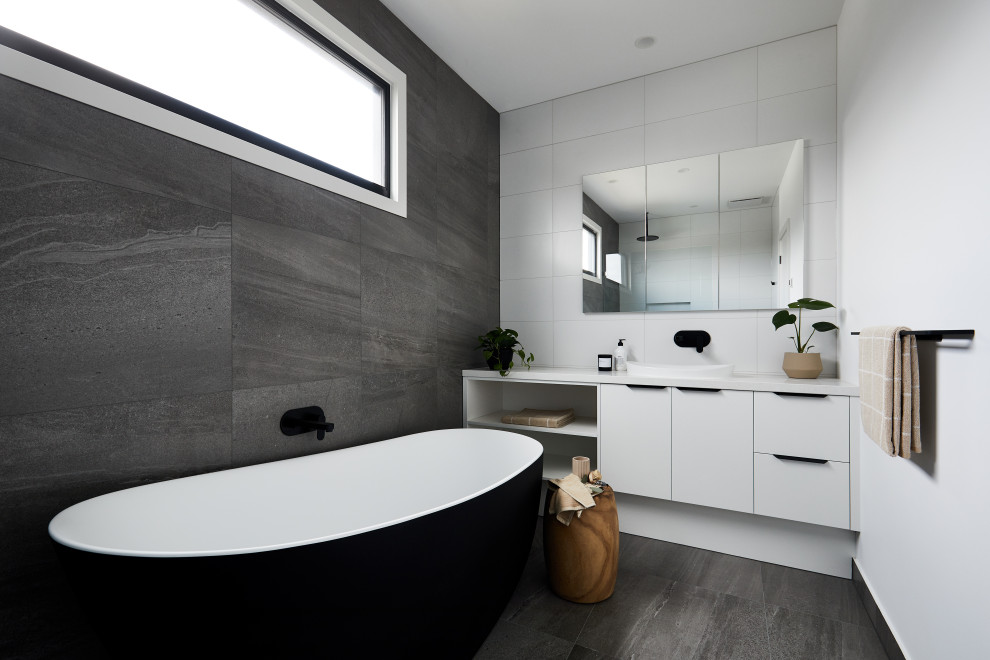 Photo of a mid-sized contemporary kids bathroom in Melbourne with white cabinets, a freestanding tub, gray tile, multi-coloured walls, grey floor, an open shower, white benchtops and a single vanity.