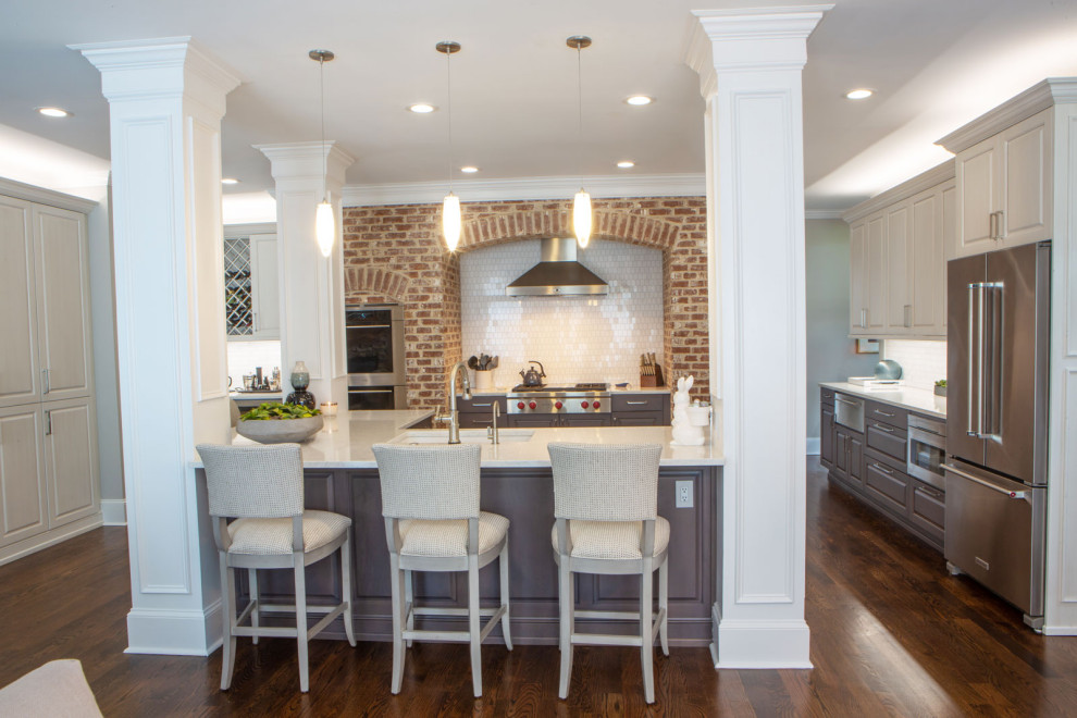 This is an example of a large country open plan kitchen in Atlanta with an undermount sink, grey cabinets, white splashback, brick splashback, stainless steel appliances and medium hardwood floors.