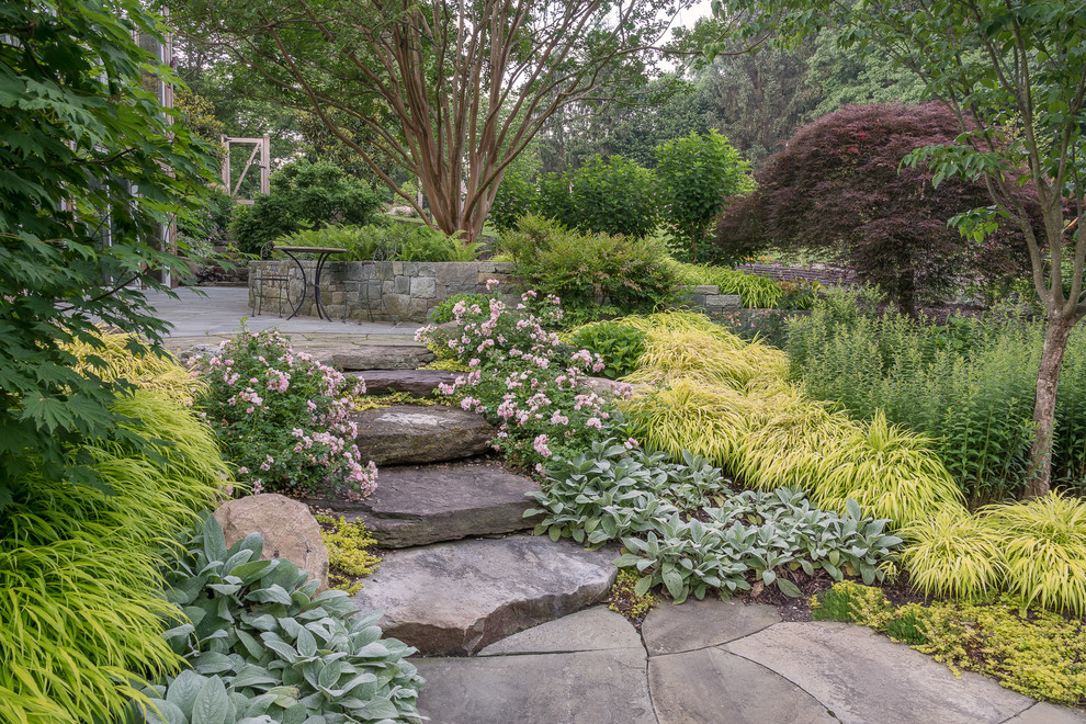 This is an example of an expansive arts and crafts side yard shaded garden in DC Metro with a retaining wall and natural stone pavers.