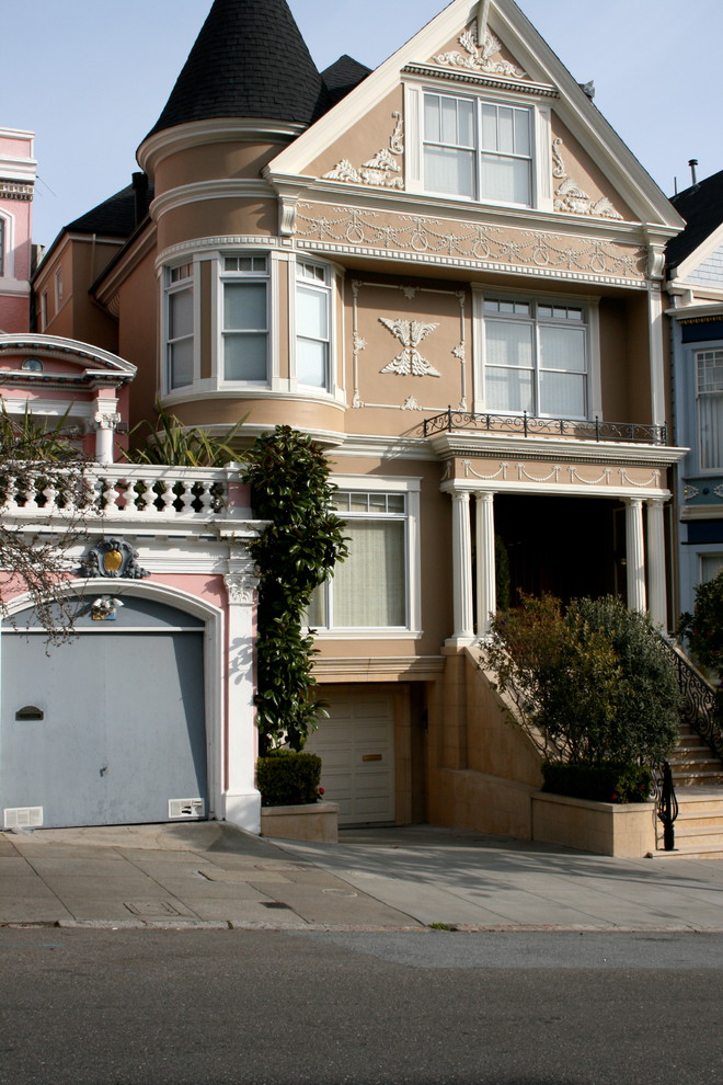 Photo of a large traditional three-storey stucco brown exterior in San Francisco with a gable roof.