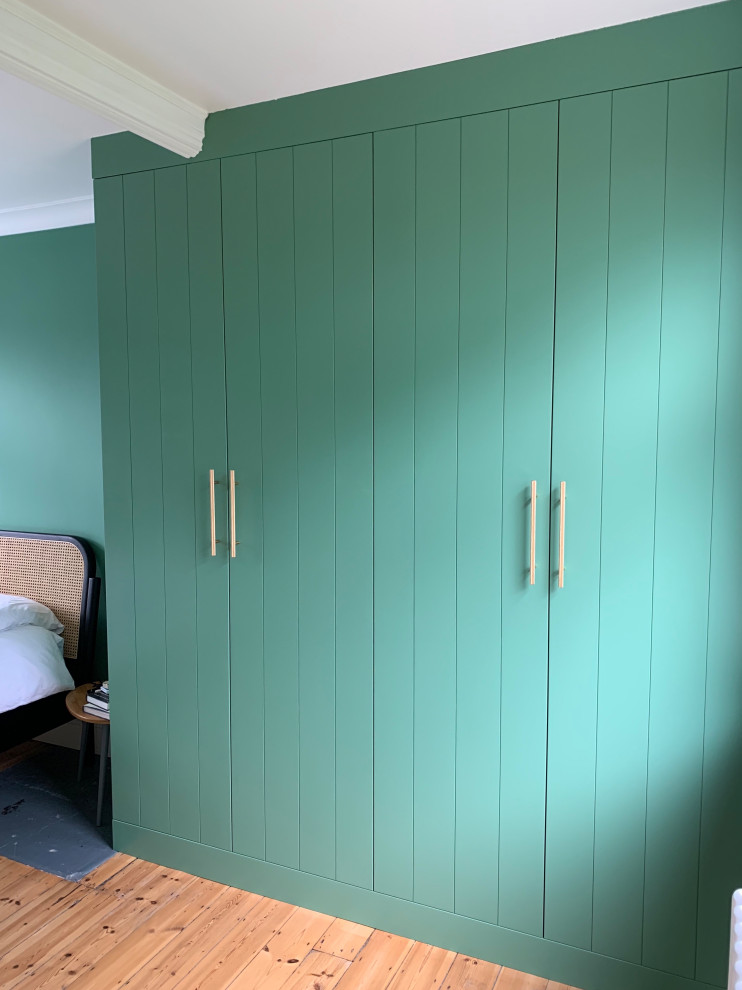 Mittelgroßes Modernes Ankleidezimmer mit Einbauschrank, flächenbündigen Schrankfronten, grünen Schränken und braunem Holzboden in London