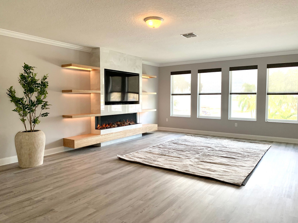 Inspiration for a large transitional loft-style family room in Orlando with grey walls, vinyl floors, a standard fireplace, a tile fireplace surround, a built-in media wall and grey floor.