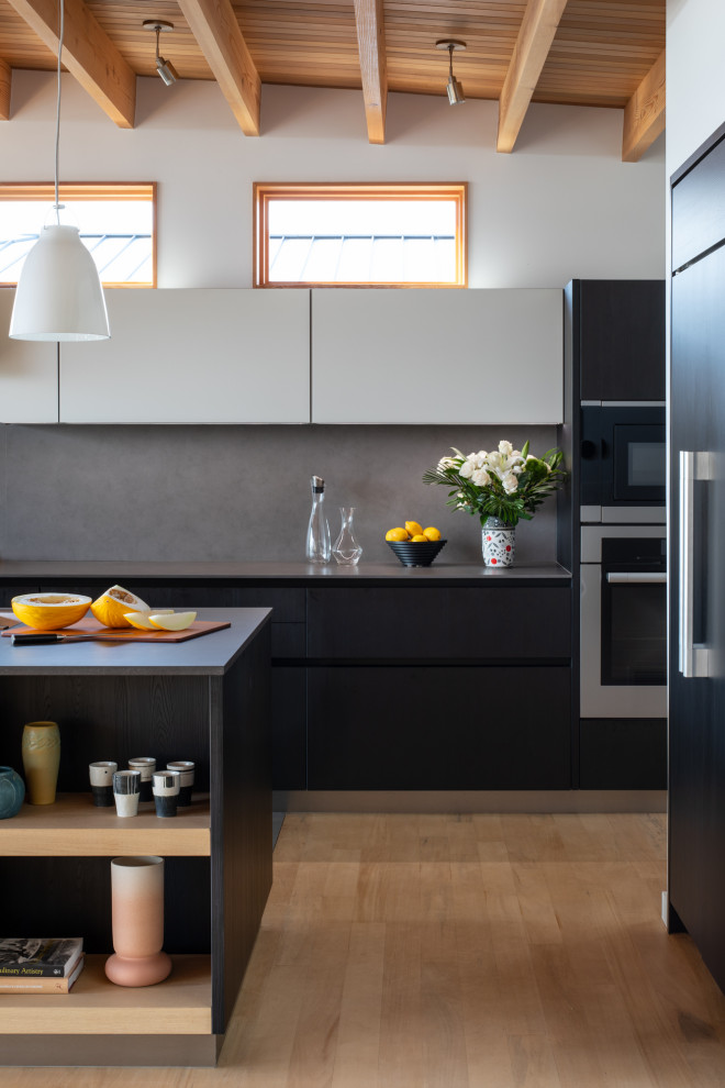 Mid-sized modern galley eat-in kitchen in Seattle with an undermount sink, flat-panel cabinets, dark wood cabinets, solid surface benchtops, grey splashback, porcelain splashback, panelled appliances, with island, yellow floor, grey benchtop and wood.
