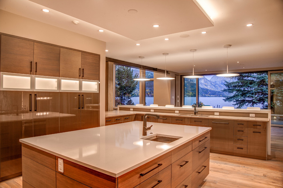 This is an example of a country u-shaped kitchen in Denver with an undermount sink, flat-panel cabinets, solid surface benchtops, light hardwood floors and with island.