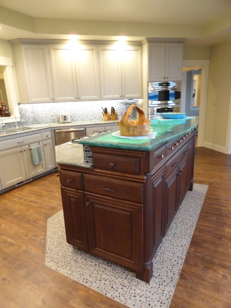 Large beach style l-shaped eat-in kitchen in Seattle with an undermount sink, recessed-panel cabinets, dark wood cabinets, green splashback, glass tile splashback, stainless steel appliances, dark hardwood floors, with island, glass benchtops and turquoise benchtop.
