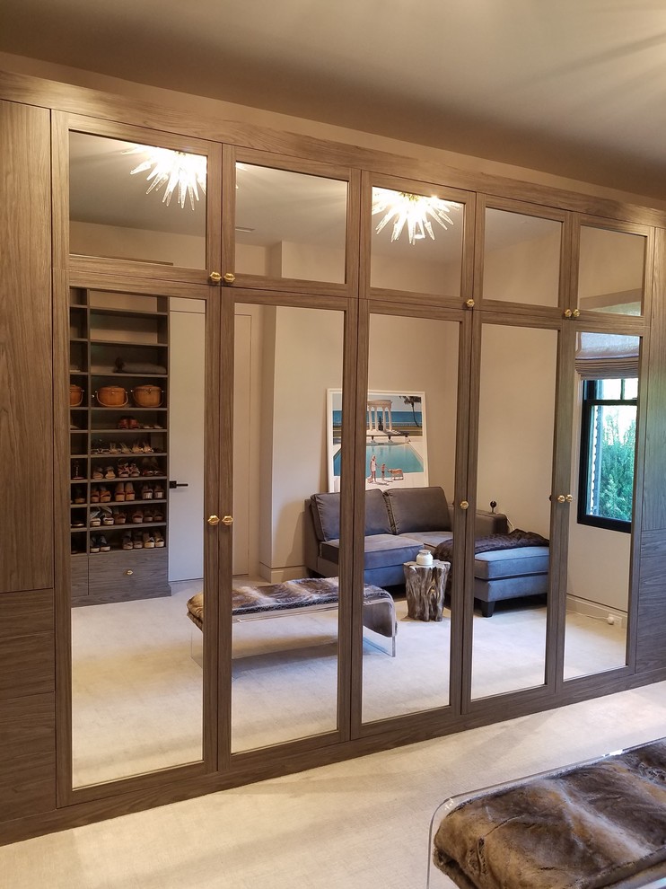Inspiration for a large traditional gender neutral walk-in wardrobe in New York with open cabinets, dark wood cabinets, carpet and beige floors.