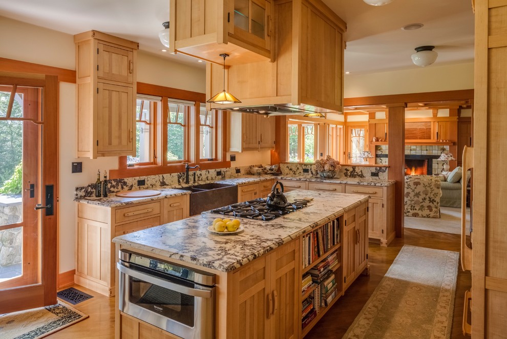 Inspiration for a large arts and crafts u-shaped eat-in kitchen in Portland Maine with a farmhouse sink, recessed-panel cabinets, light wood cabinets, granite benchtops, brown splashback, stone slab splashback, stainless steel appliances, light hardwood floors and with island.