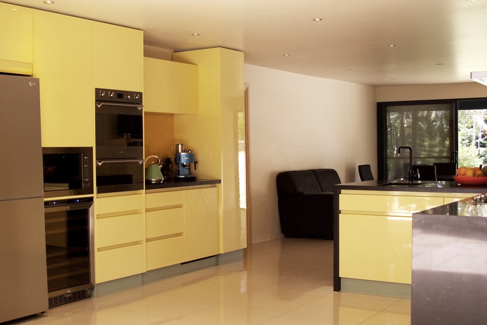 Design ideas for a mid-sized contemporary l-shaped open plan kitchen in Adelaide with an undermount sink, flat-panel cabinets, yellow cabinets, quartz benchtops, yellow splashback, glass sheet splashback, stainless steel appliances, porcelain floors, a peninsula and beige floor.