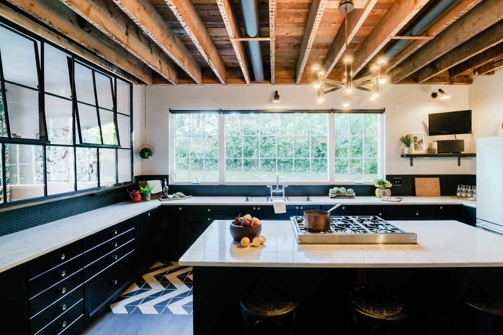 This is an example of an expansive industrial eat-in kitchen in Providence with an undermount sink, flat-panel cabinets, black cabinets, quartz benchtops, black splashback, ceramic splashback, stainless steel appliances, ceramic floors, with island, multi-coloured floor and white benchtop.
