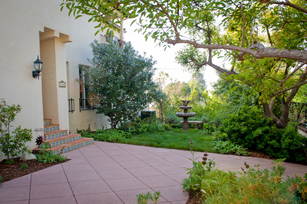 This is an example of a large mediterranean front yard patio in Los Angeles with a water feature, tile and no cover.