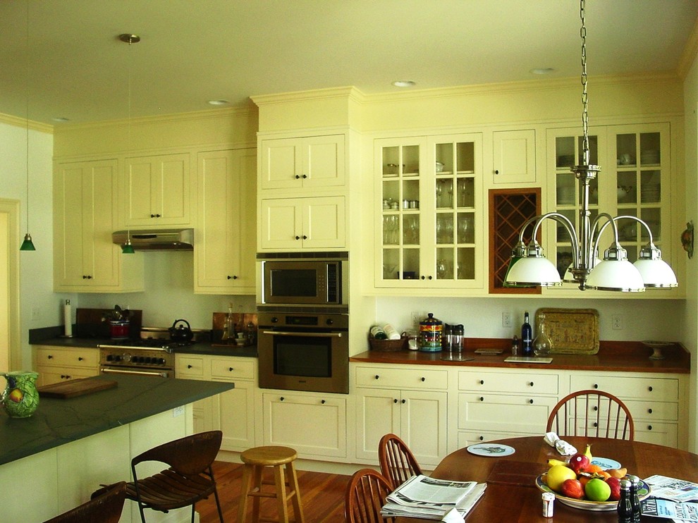 Inspiration for a large country single-wall eat-in kitchen in Providence with recessed-panel cabinets, yellow cabinets, wood benchtops, white splashback, light hardwood floors and with island.