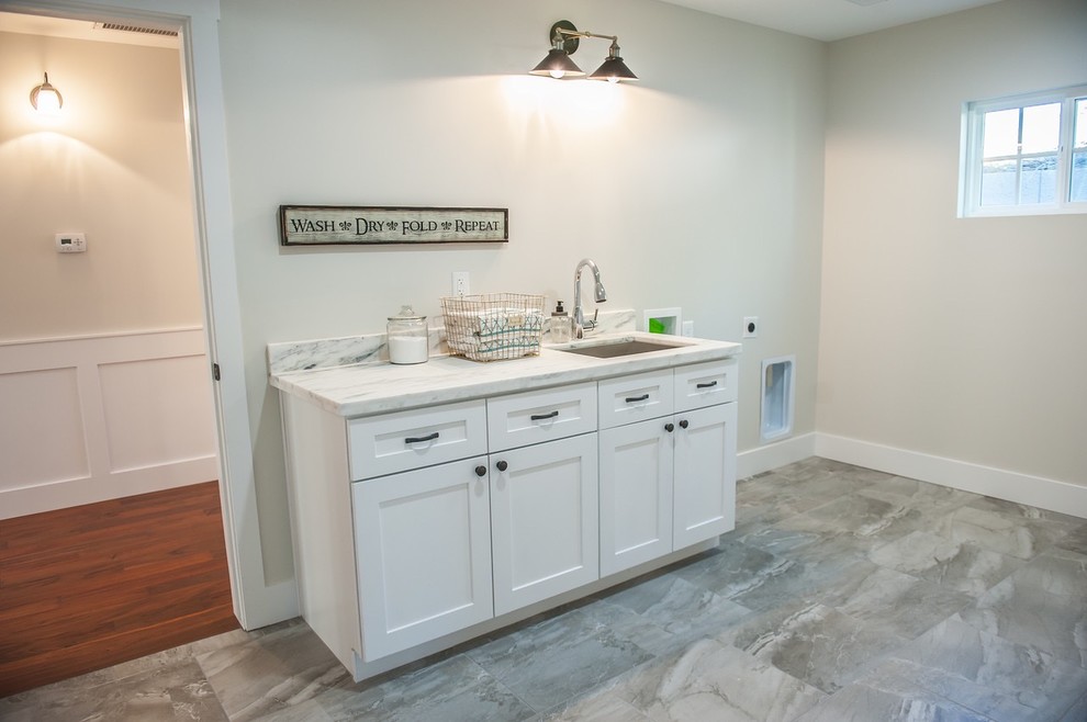 Photo of a large arts and crafts dedicated laundry room in Phoenix with a drop-in sink, shaker cabinets, white cabinets, marble benchtops, grey walls and ceramic floors.