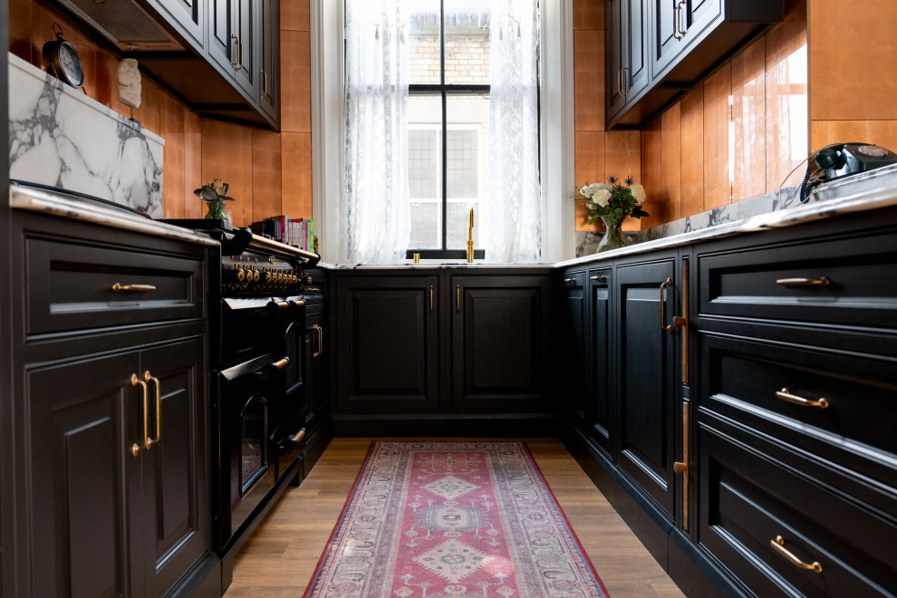 Design ideas for a small traditional u-shaped separate kitchen in London with an integrated sink, raised-panel cabinets, black cabinets, quartzite benchtops, white splashback, engineered quartz splashback, black appliances, medium hardwood floors, brown floor and white benchtop.