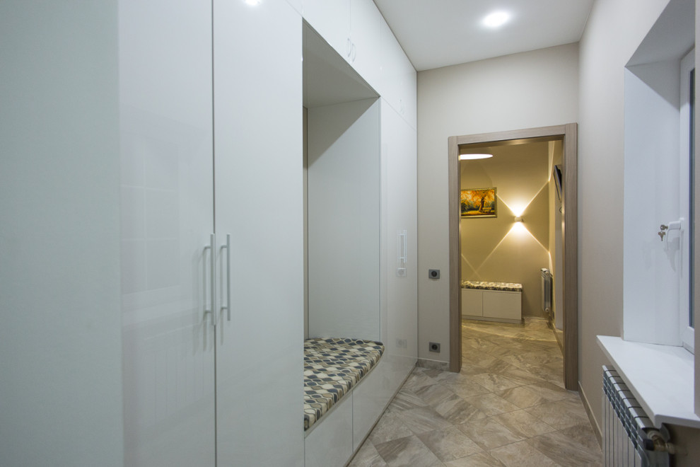 Идея дизайна: гардеробная комната среднего размера, унисекс в современном стиле с плоскими фасадами, белыми фасадами, полом из керамической плитки и бежевым полом