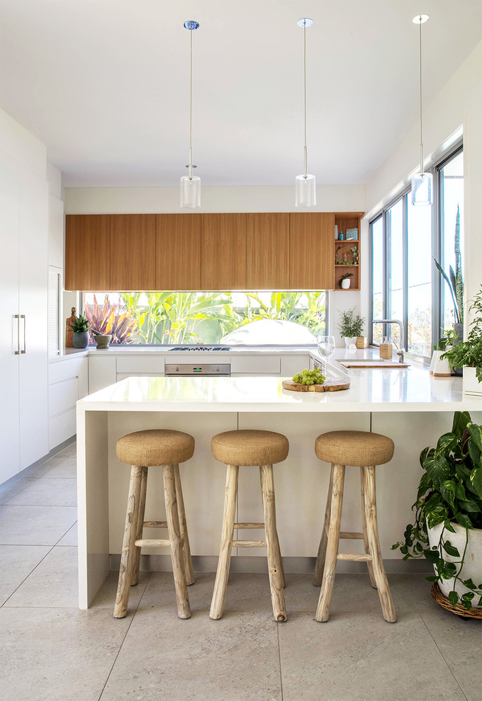 Photo of a tropical u-shaped kitchen in Sunshine Coast with an undermount sink, flat-panel cabinets, medium wood cabinets, window splashback, panelled appliances, a peninsula and beige floor.