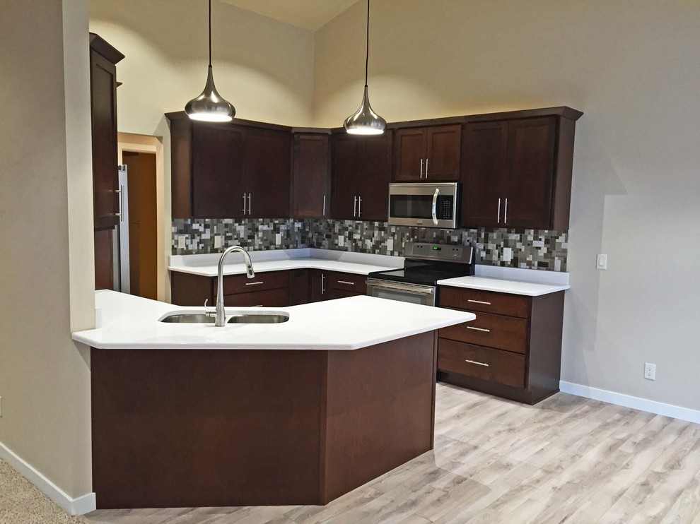 Mid-sized modern galley eat-in kitchen in Milwaukee with an undermount sink, shaker cabinets, dark wood cabinets, quartz benchtops, multi-coloured splashback, glass tile splashback, stainless steel appliances and a peninsula.