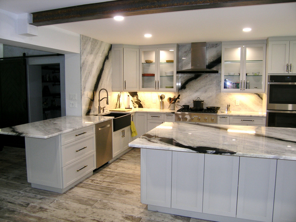 Lantlig inredning av ett stort grå grått kök, med en enkel diskho, skåp i shakerstil, vita skåp, granitbänkskiva, grått stänkskydd, rostfria vitvaror, klinkergolv i porslin, en köksö och grått golv