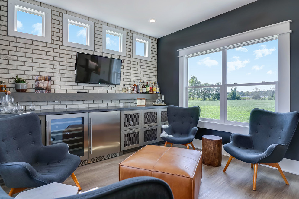 Mid-sized contemporary single-wall wet bar in Grand Rapids with grey cabinets, white splashback, subway tile splashback, light hardwood floors, beige floor, grey benchtop and a drop-in sink.
