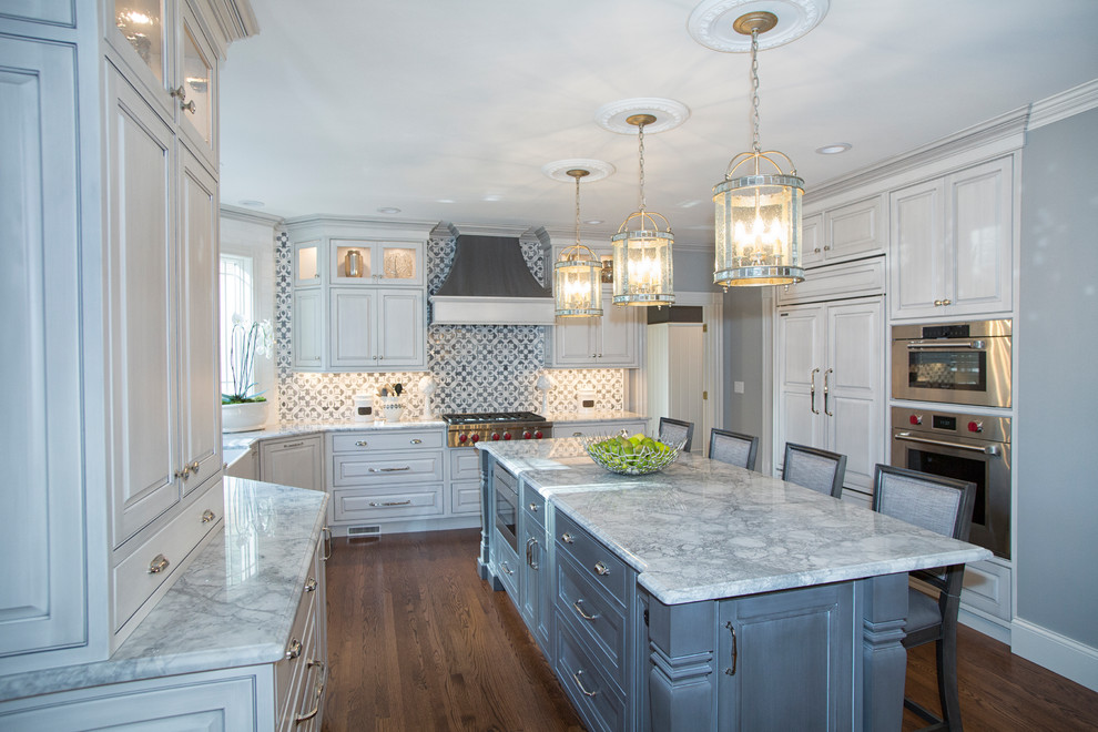 Design ideas for a large transitional u-shaped eat-in kitchen in Boston with stainless steel appliances, medium hardwood floors, with island, brown floor, a farmhouse sink, granite benchtops, white cabinets, grey splashback, porcelain splashback, grey benchtop and raised-panel cabinets.