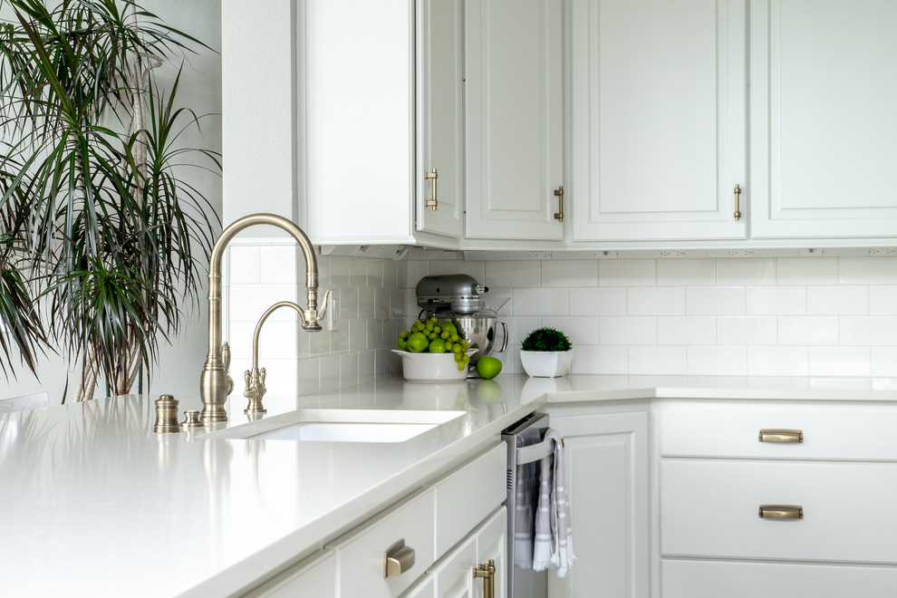 Transitional u-shaped travertine floor and brown floor open concept kitchen photo in Seattle with an undermount sink, raised-panel cabinets, white cabinets, quartz countertops, white backsplash, porcelain backsplash, stainless steel appliances, an island and white countertops